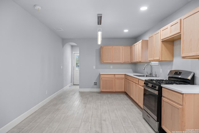 kitchen with gas range, light brown cabinets, light hardwood / wood-style floors, and sink