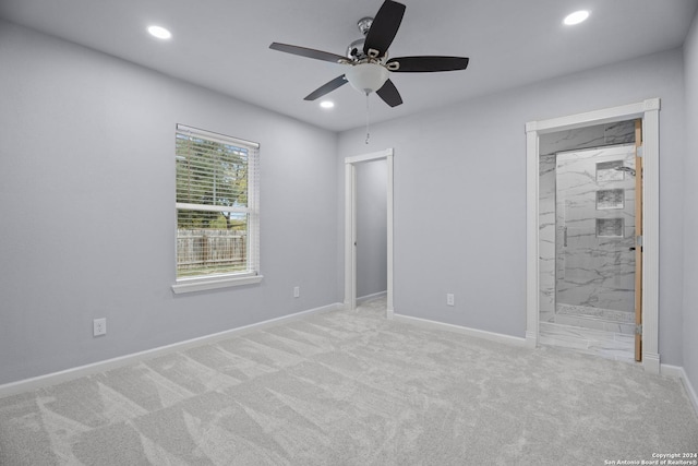 unfurnished bedroom featuring ceiling fan, a closet, light colored carpet, and ensuite bath