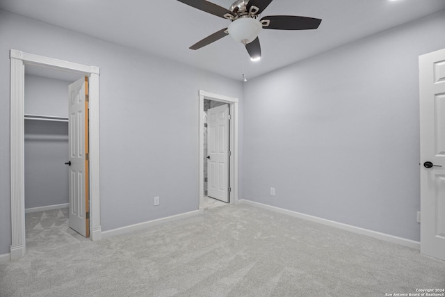 unfurnished bedroom featuring ceiling fan, a walk in closet, light carpet, and a closet