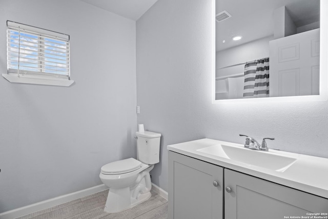 bathroom with hardwood / wood-style floors, vanity, toilet, and curtained shower