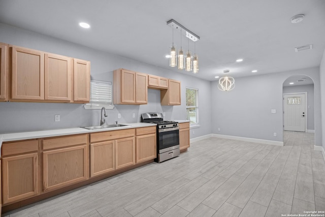 kitchen featuring light brown cabinets, sink, light hardwood / wood-style floors, decorative light fixtures, and gas stove