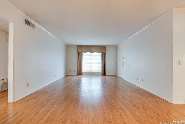 spare room featuring light wood-type flooring and crown molding