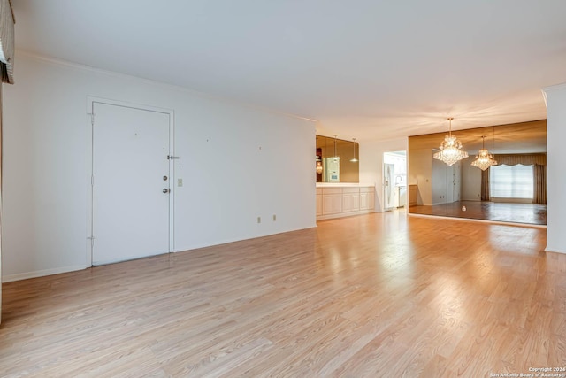 interior space with light hardwood / wood-style floors, crown molding, and a chandelier