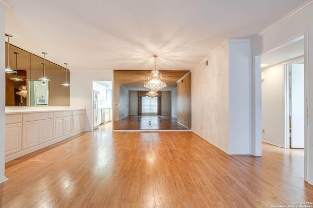 unfurnished living room with crown molding, light hardwood / wood-style flooring, and an inviting chandelier