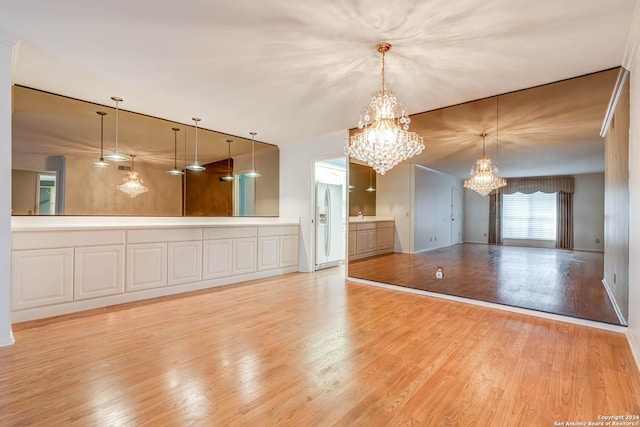 unfurnished living room featuring light hardwood / wood-style floors and a notable chandelier