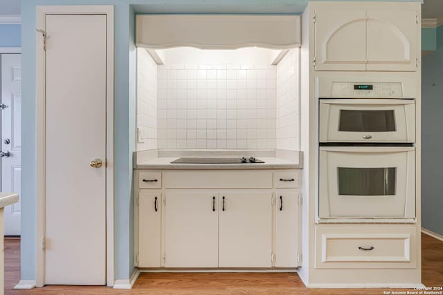 kitchen with double oven, light hardwood / wood-style flooring, white cabinets, and black electric stovetop