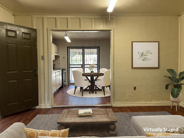 living room with a textured ceiling, crown molding, and dark wood-type flooring