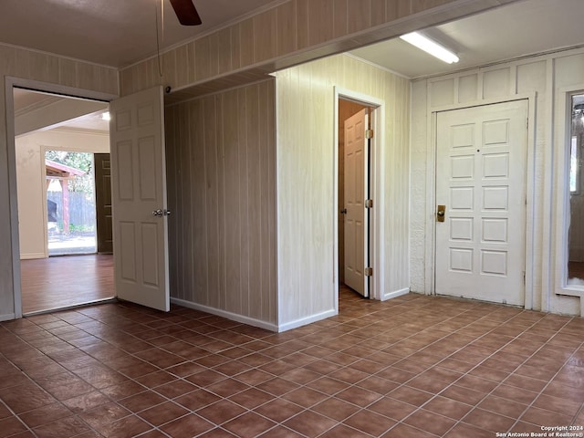 unfurnished room featuring ceiling fan, wood walls, and ornamental molding