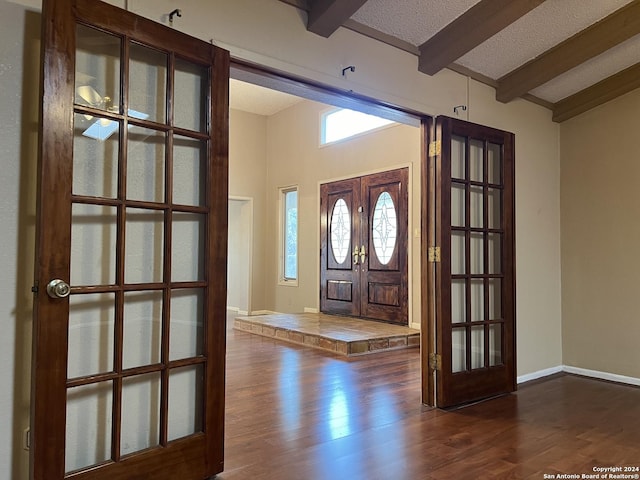 foyer entrance with dark hardwood / wood-style floors, lofted ceiling with beams, a textured ceiling, and french doors