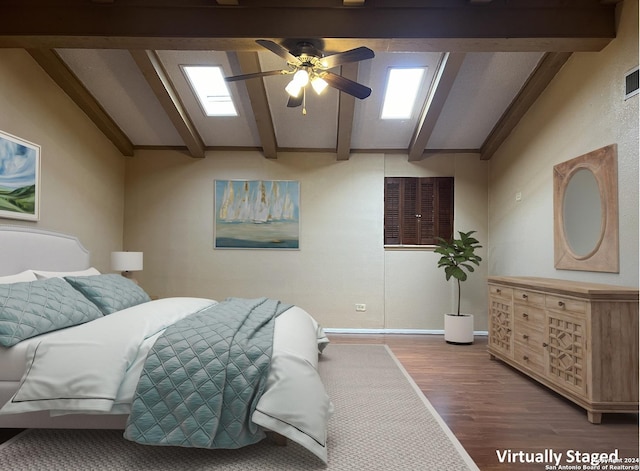 bedroom with ceiling fan, vaulted ceiling with skylight, and hardwood / wood-style flooring