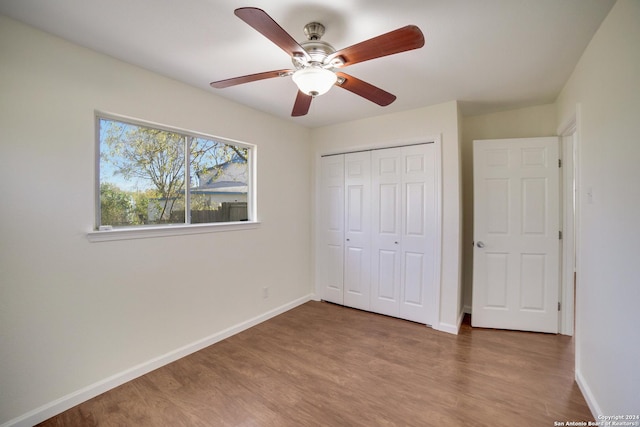 unfurnished bedroom featuring hardwood / wood-style floors, a closet, and ceiling fan