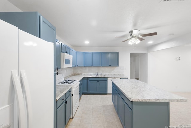 kitchen with white appliances, blue cabinets, ceiling fan, sink, and a center island