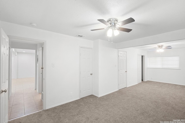 carpeted empty room featuring ceiling fan and a textured ceiling