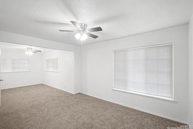 carpeted spare room featuring ceiling fan and a textured ceiling