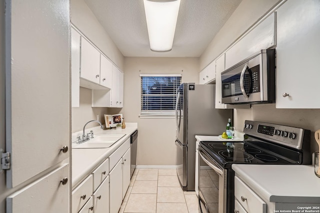 kitchen with sink, stainless steel appliances, white cabinets, a textured ceiling, and light tile patterned flooring