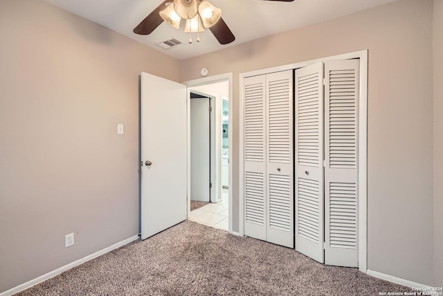 unfurnished bedroom with ceiling fan, light carpet, and a closet