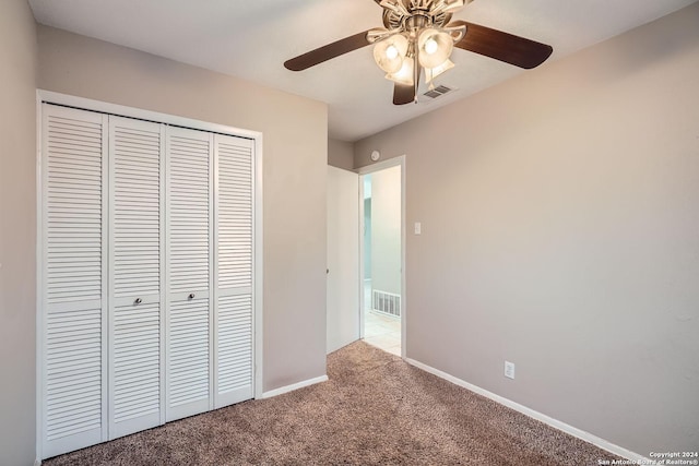 unfurnished bedroom featuring ceiling fan, a closet, and light colored carpet