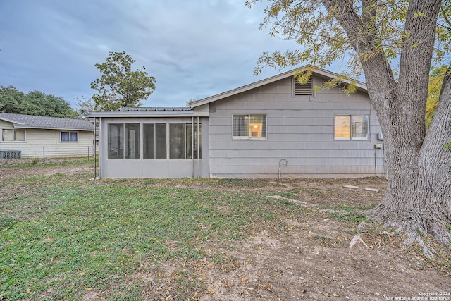 rear view of house featuring central air condition unit, a sunroom, and a yard