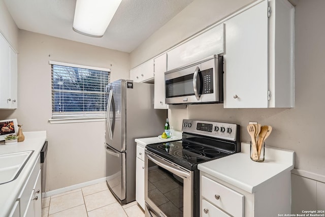 kitchen with sink, light tile patterned floors, a textured ceiling, white cabinets, and appliances with stainless steel finishes