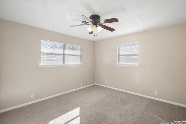 carpeted empty room with ceiling fan, a textured ceiling, and a wealth of natural light