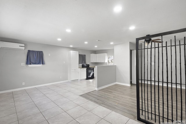 kitchen with white cabinets, black electric range, ceiling fan, light hardwood / wood-style floors, and a wall unit AC