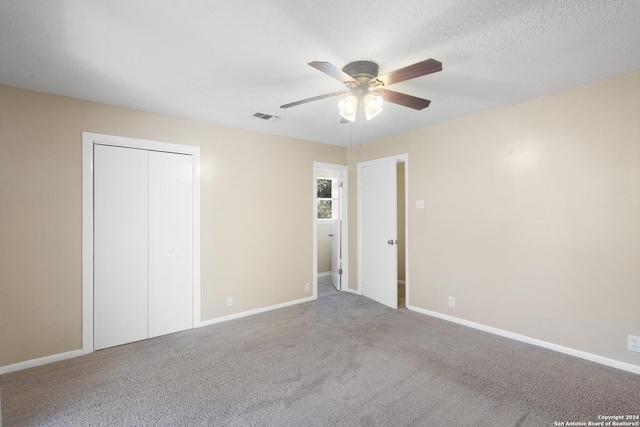 unfurnished bedroom featuring carpet, ceiling fan, a textured ceiling, and a closet