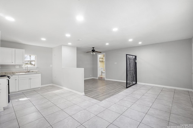 unfurnished living room with light tile patterned flooring, ceiling fan, and sink