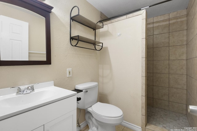 bathroom with a tile shower, tile patterned flooring, a textured ceiling, toilet, and vanity