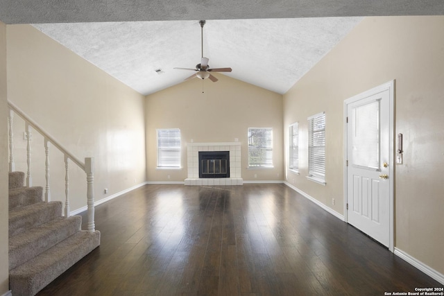 unfurnished living room featuring high vaulted ceiling, a tile fireplace, ceiling fan, dark hardwood / wood-style floors, and a textured ceiling