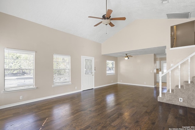 unfurnished living room featuring dark wood-type flooring, high vaulted ceiling, a healthy amount of sunlight, and a textured ceiling