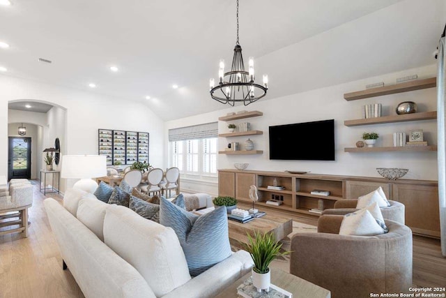 living room with a notable chandelier, light hardwood / wood-style floors, and vaulted ceiling