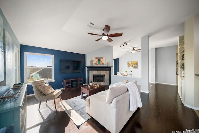 living room featuring dark wood-type flooring, lofted ceiling, a tile fireplace, and ceiling fan