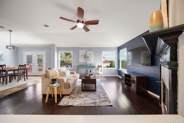 living room featuring ceiling fan, french doors, dark wood-type flooring, and a fireplace