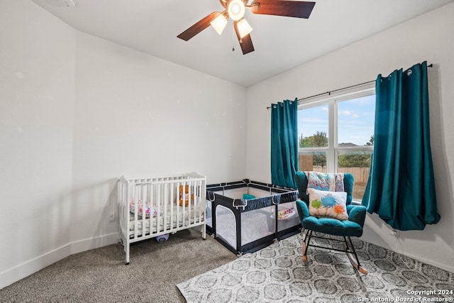 bedroom with carpet flooring, ceiling fan, and a crib