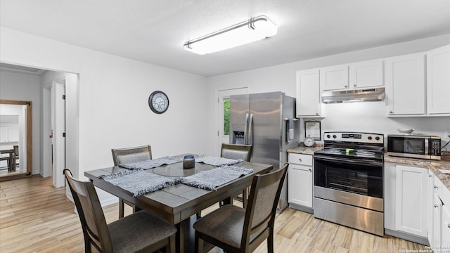 kitchen with light stone counters, light hardwood / wood-style floors, a textured ceiling, white cabinets, and appliances with stainless steel finishes