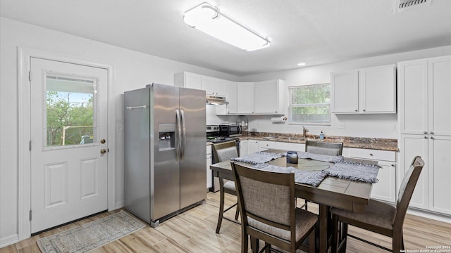 kitchen featuring white cabinets, light wood-type flooring, stainless steel appliances, and a textured ceiling