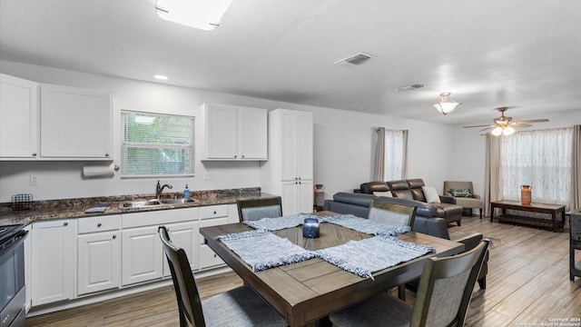 dining area featuring ceiling fan, sink, wood-type flooring, and a textured ceiling