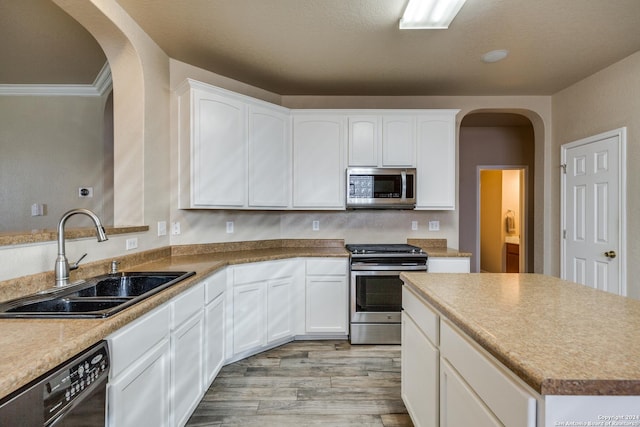 kitchen with white cabinetry, sink, crown molding, appliances with stainless steel finishes, and light wood-type flooring