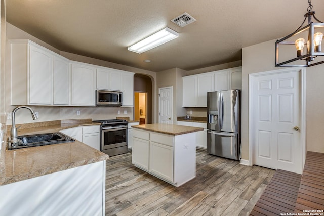 kitchen with pendant lighting, a center island, sink, appliances with stainless steel finishes, and light hardwood / wood-style floors