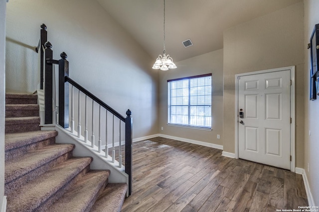 foyer entrance featuring hardwood / wood-style flooring, high vaulted ceiling, and a chandelier