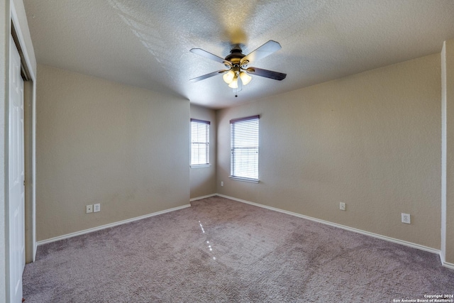 carpeted empty room with ceiling fan and a textured ceiling