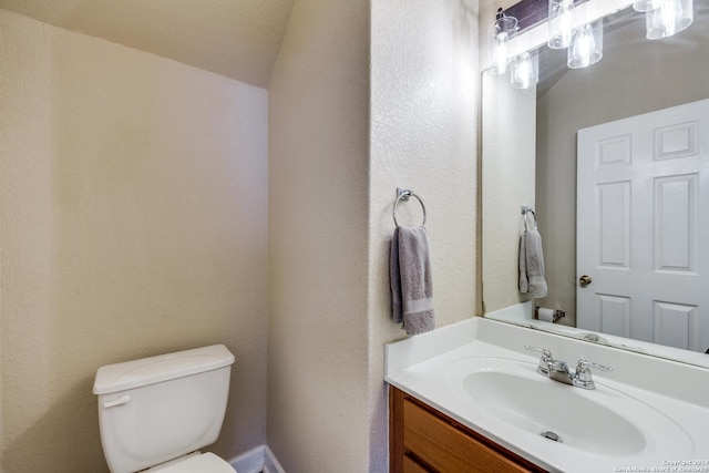 bathroom with a textured ceiling, vanity, toilet, and lofted ceiling