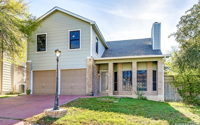 view of front of home featuring central AC unit, a front yard, and a garage