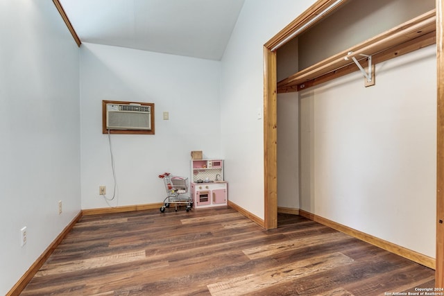 interior space featuring dark hardwood / wood-style floors, an AC wall unit, and lofted ceiling