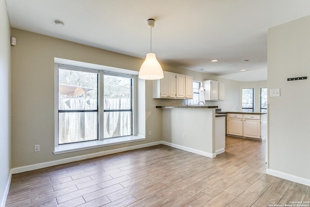 kitchen featuring kitchen peninsula, a wealth of natural light, pendant lighting, and light wood-type flooring