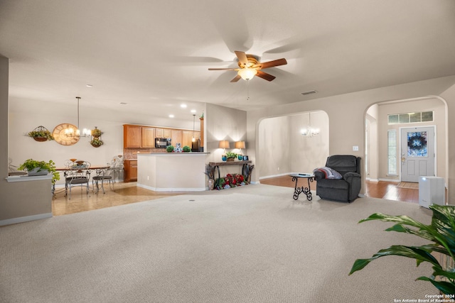 interior space with light carpet and ceiling fan with notable chandelier