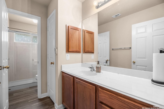 bathroom with hardwood / wood-style floors, vanity, toilet, and a shower with shower door