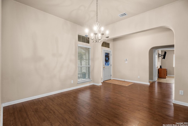 unfurnished room featuring a notable chandelier and dark hardwood / wood-style floors