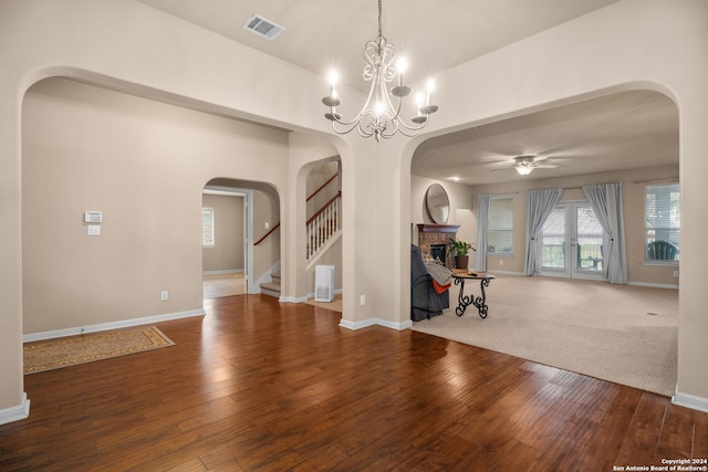 interior space featuring hardwood / wood-style floors, ceiling fan with notable chandelier, a fireplace, and french doors