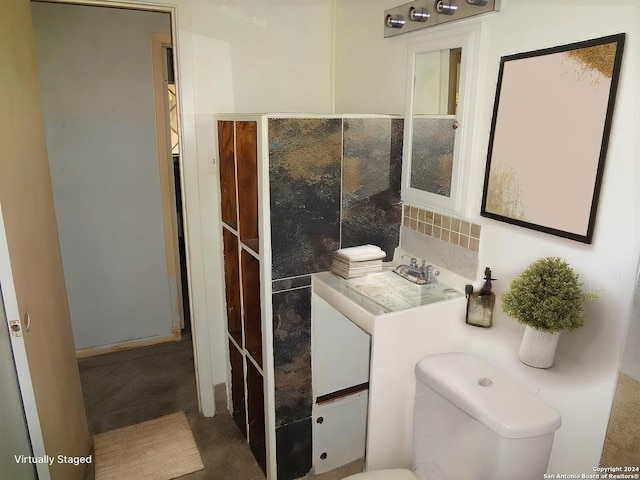 bathroom featuring concrete flooring, backsplash, toilet, and sink